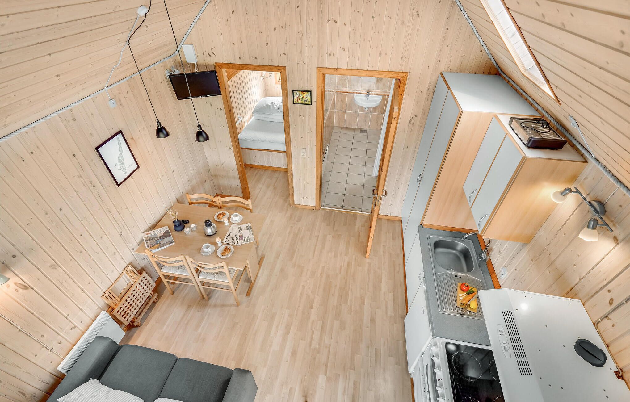 A compact, wooden-floored room with a dining area, a kitchenette, and a small seating area.