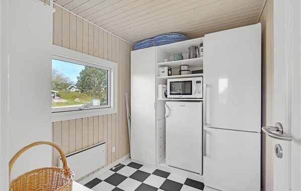A compact kitchen with a window, white appliances, and a checkered floor. - Gorgeous home in Millinge with sauna (Millinge)