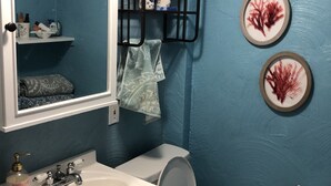 Ein Badezimmer mit Waschbecken, Toilette und einem Ablagefach mit Handtüchern.