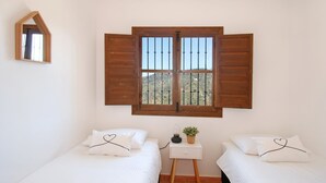 Ein Schlafzimmer mit zwei Betten, einem kleinen Nachttisch, einem Spiegel und einem Fenster mit Holzläden.
