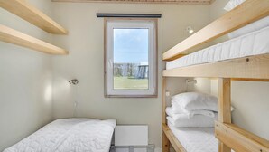 A compact room with bunk beds, a window with a view of the outdoors, and a radiator. - Cozy home in Tranekær (Tranekær)
