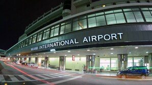 El exterior del Aeropuerto Internacional de Miami, con una vista clara de la entrada principal y el nombre 'MIAMI INTERNATIONAL AIRPORT' visible.