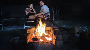 Dos personas sentadas junto a una fogata por la noche.