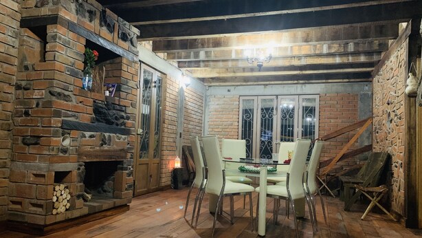 Un comedor rústico con chimenea de ladrillo, vigas de madera y una mesa de vidrio.