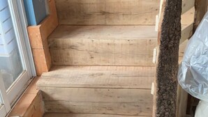 Una escalera de madera con borde de piedra y piso de baldosas.