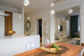 A modern kitchen with white cabinetry, a wooden island, and a dining area with a wooden table and clear chairs.