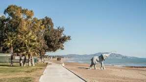 Un paseo marítimo con sendero de concreto, palmeras y una estatua grande de elefante.