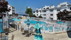 A pool area with a fenced pool, lounge chairs, and umbrellas.