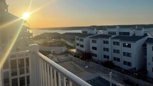 A residential area with modern buildings, a clear sky, and a view of the sea.