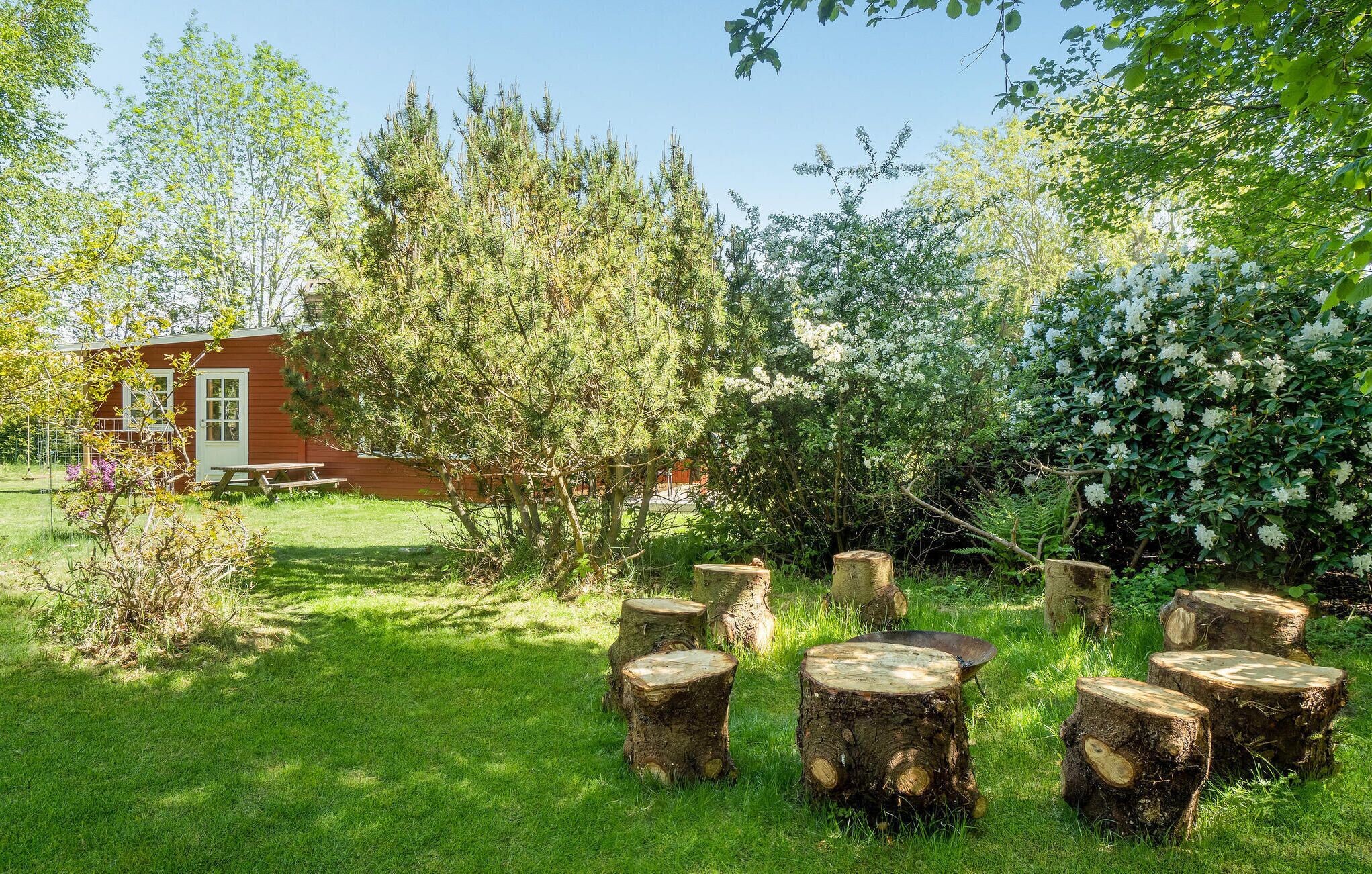 A rustic wooden cabin with a picnic table in a lush garden.