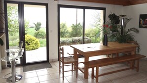 A dining area with a wooden table and bench, a chair, and a glass table with a metal base.