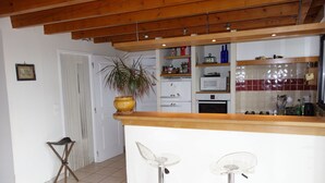 A kitchen with a wooden countertop, two bar stools, a potted plant, and a white door.
