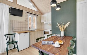 A compact kitchen with a wooden countertop, a built-in oven, and a dining area with a wooden table and chairs. - Gorgeous home in Tranekær with WiFi (Tranekær)