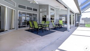 Uma área de varanda coberta com mesa, cadeiras, janelas amplas e ventiladores de teto.