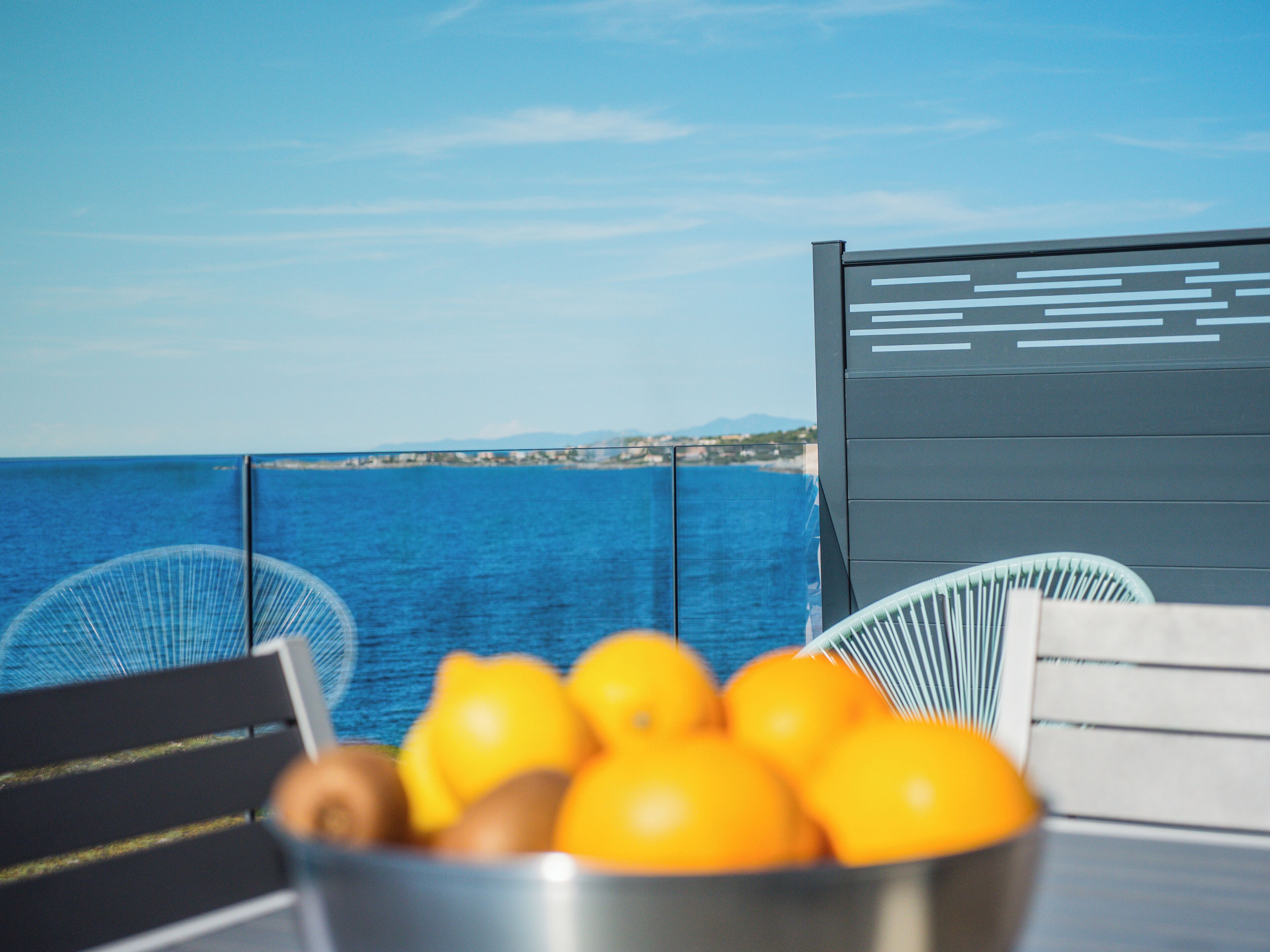 Un tavolo con una ciotola di frutta e vista sul mare.