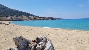 Une plage d’où l’on a une vue dégagée sur la mer, avec une ville en arrière-plan.