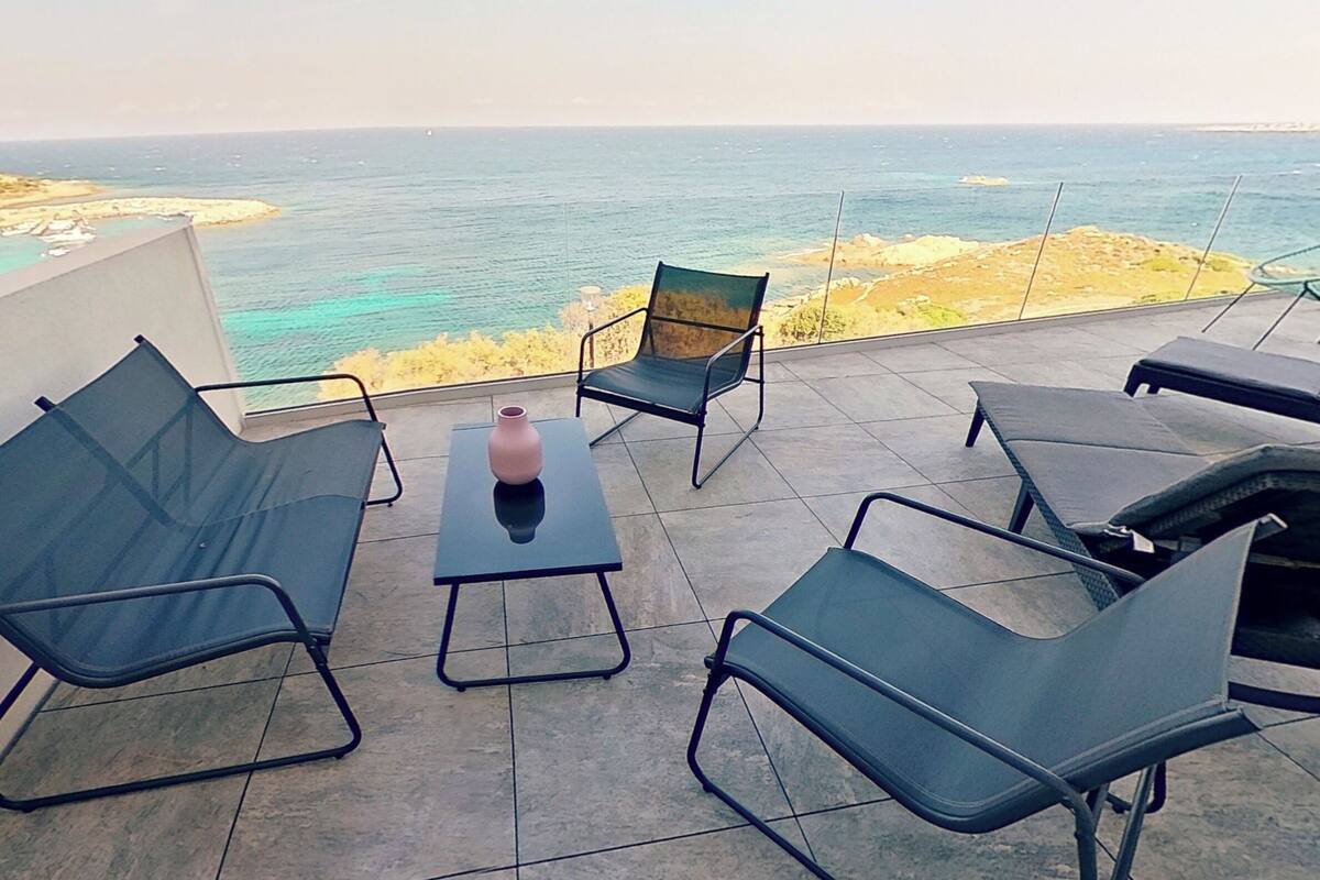 Une terrasse avec des sièges extérieurs, un vase et une vue sur la mer.