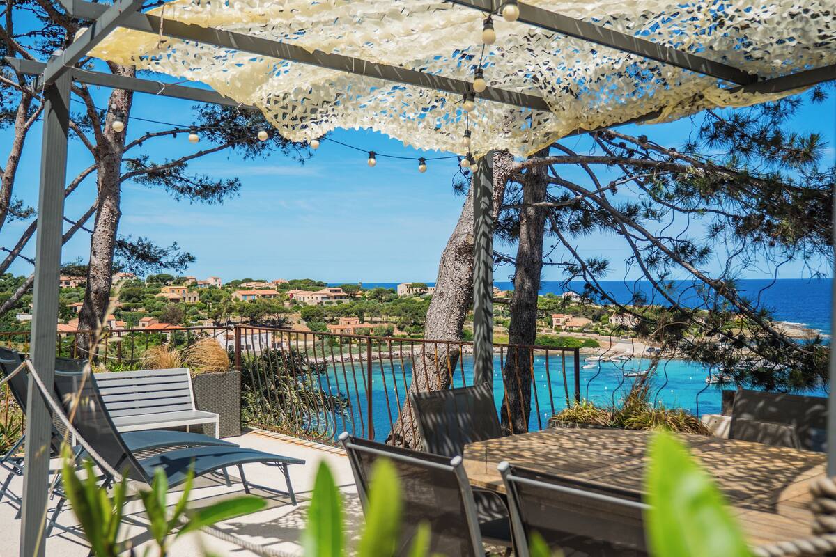Une terrasse avec des sièges extérieurs, une piscine et une vue sur la mer et la ville.