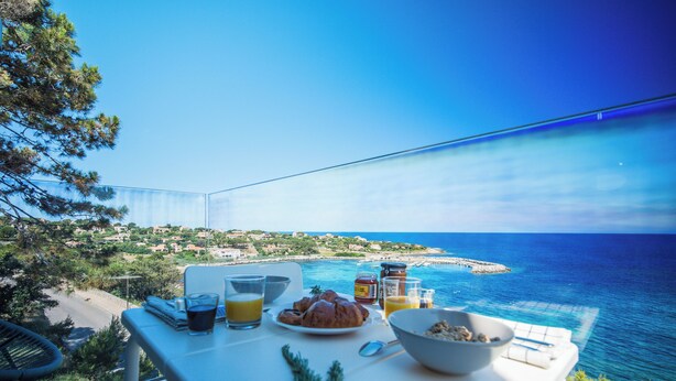 Une table dressée avec des aliments pour le petit-déjeuner, offrant une vue sur la mer.