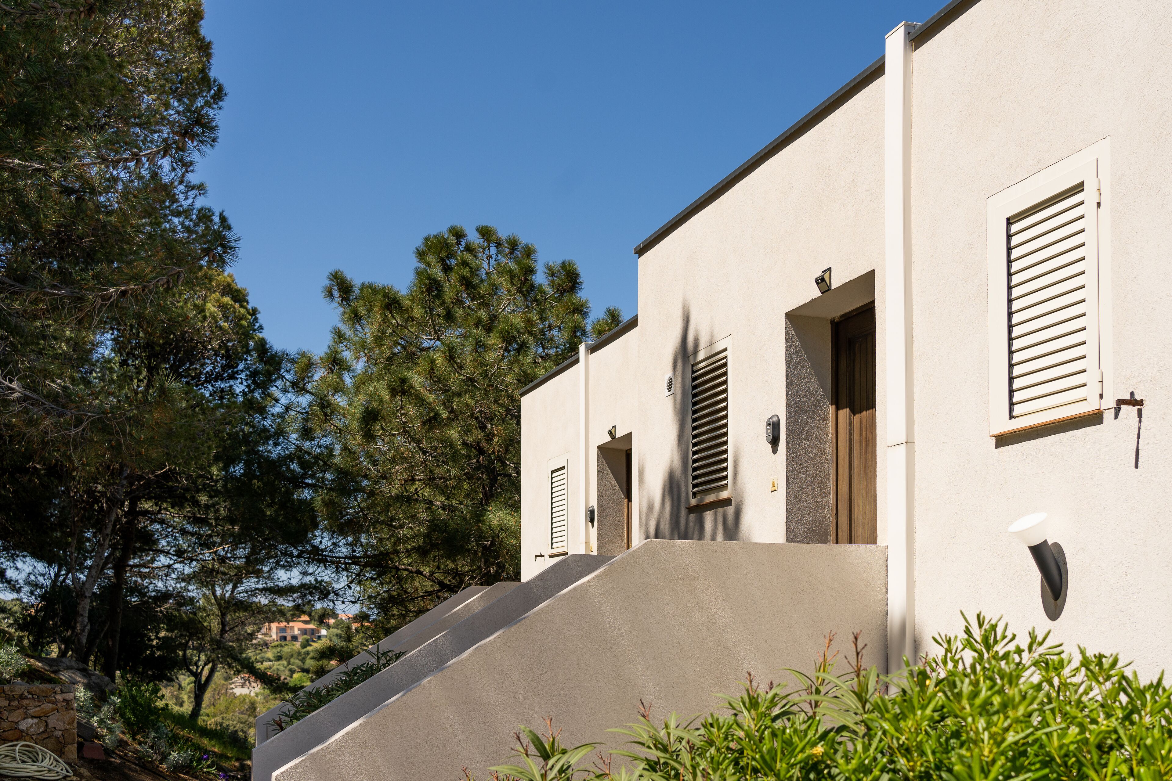 A modern building with a sloped roof, a stone wall, and a wooden door.
