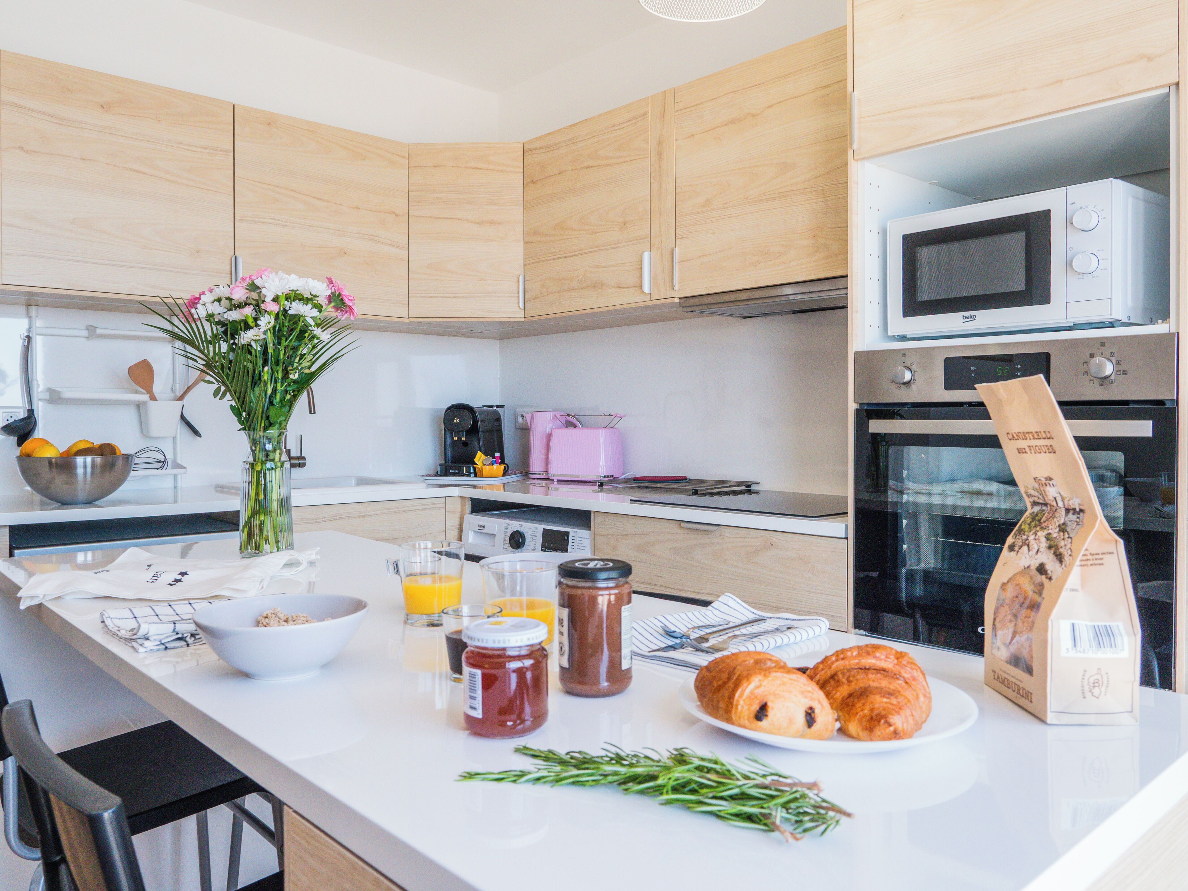 A kitchen with wooden cabinets, a microwave, an oven, a coffee maker, and a vase with flowers on the counter.