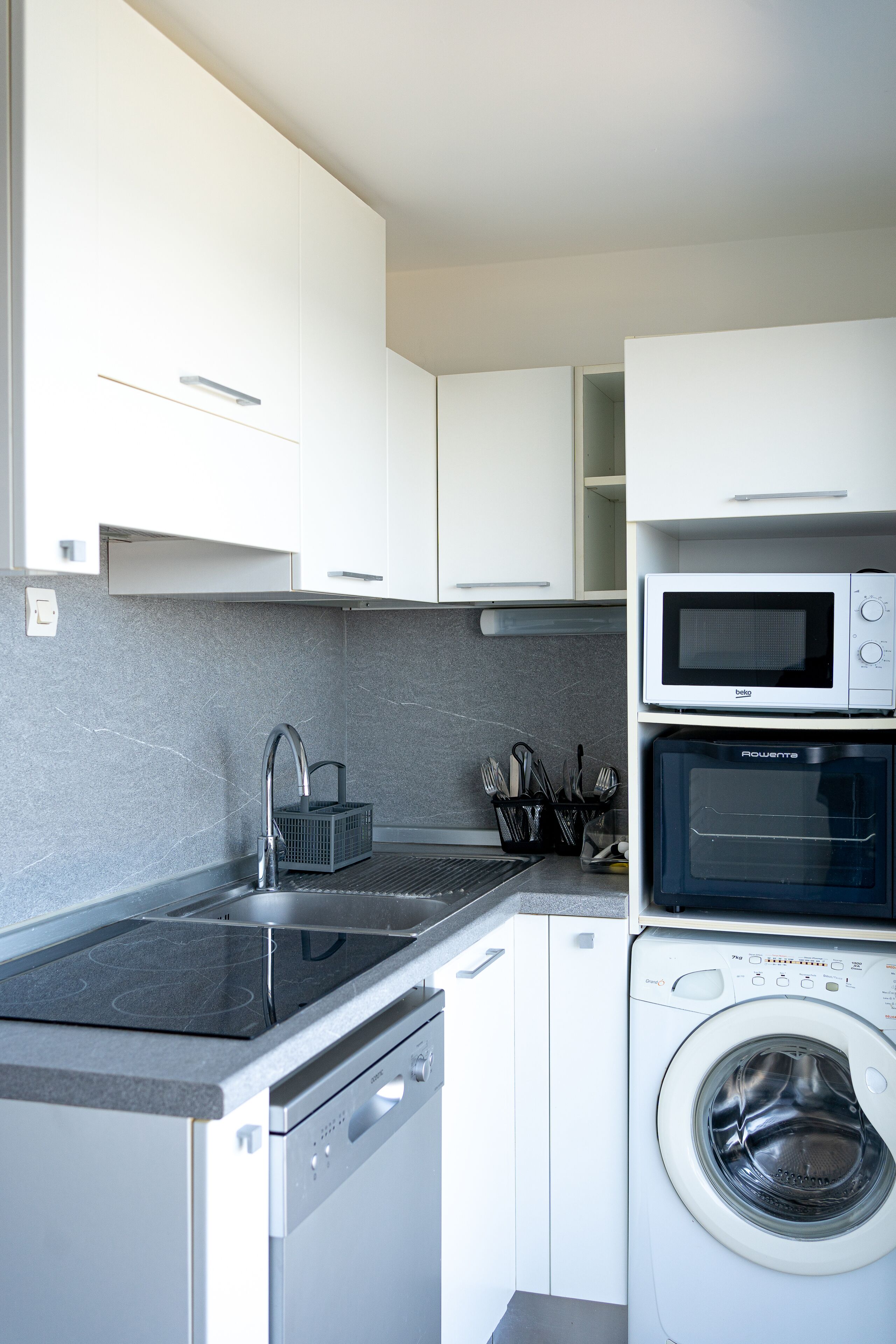 Une cuisine moderne équipée d’un lave-vaisselle, d’un four à micro-ondes et d’un lave-linge.