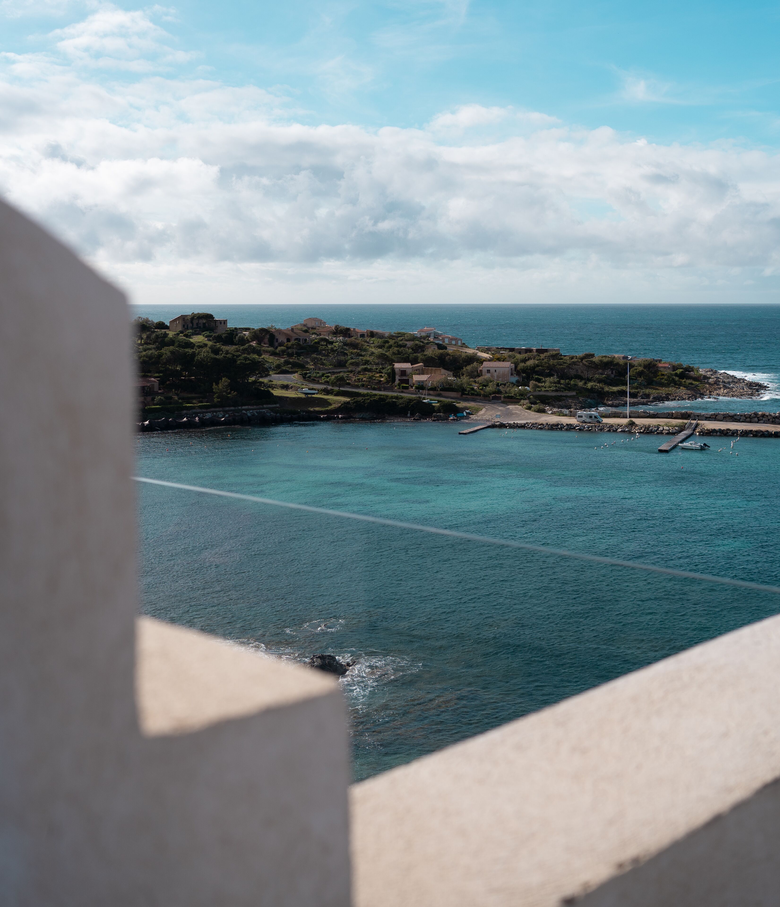 A coastal view with a clear sky, calm sea, and a rocky island with buildings.