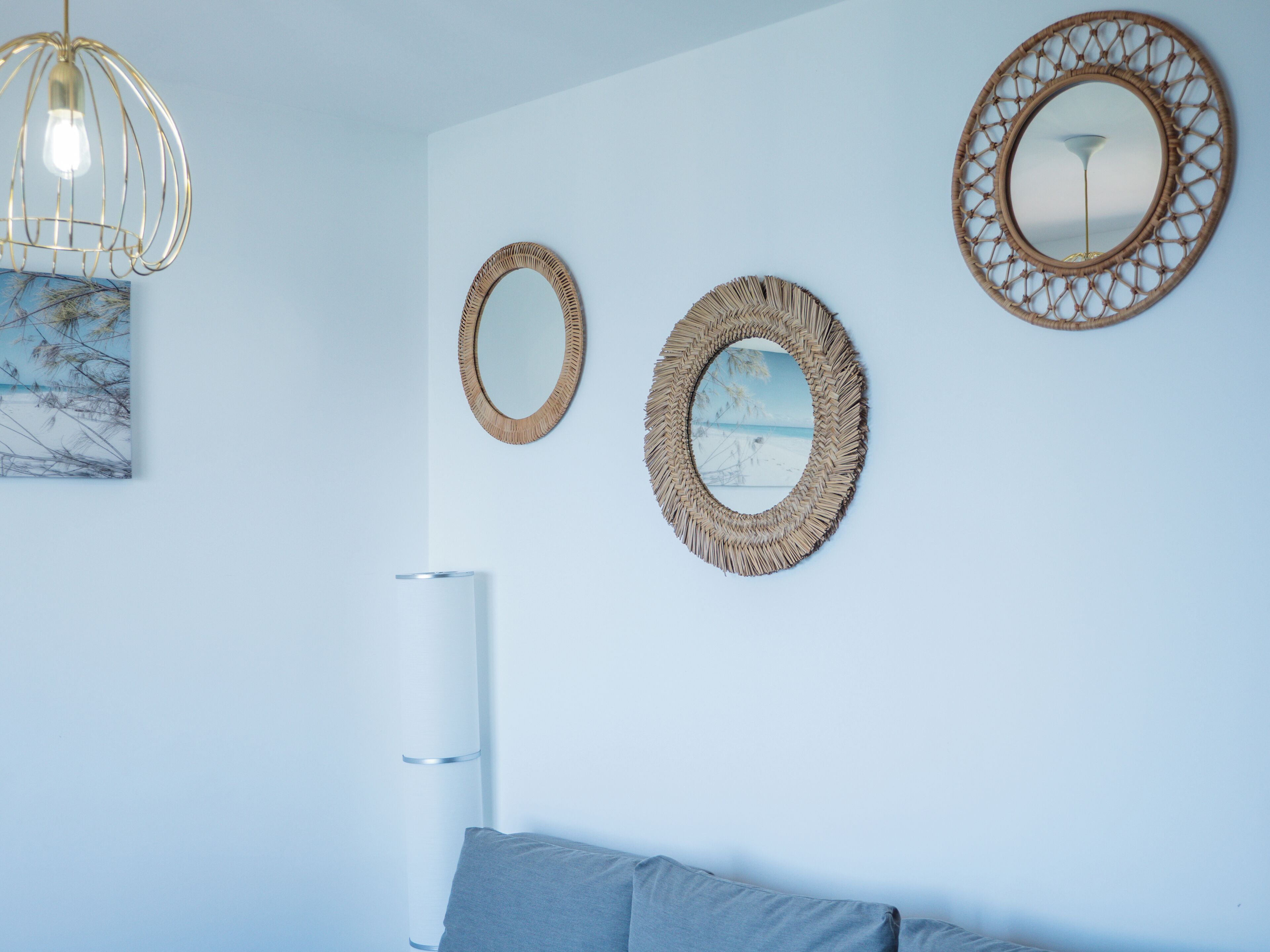 A room with a bed, a wall-mounted mirror, a hanging light fixture, and a framed picture.