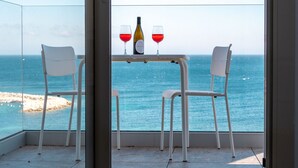 Un balcon avec une table et des chaises, donnant sur la mer.