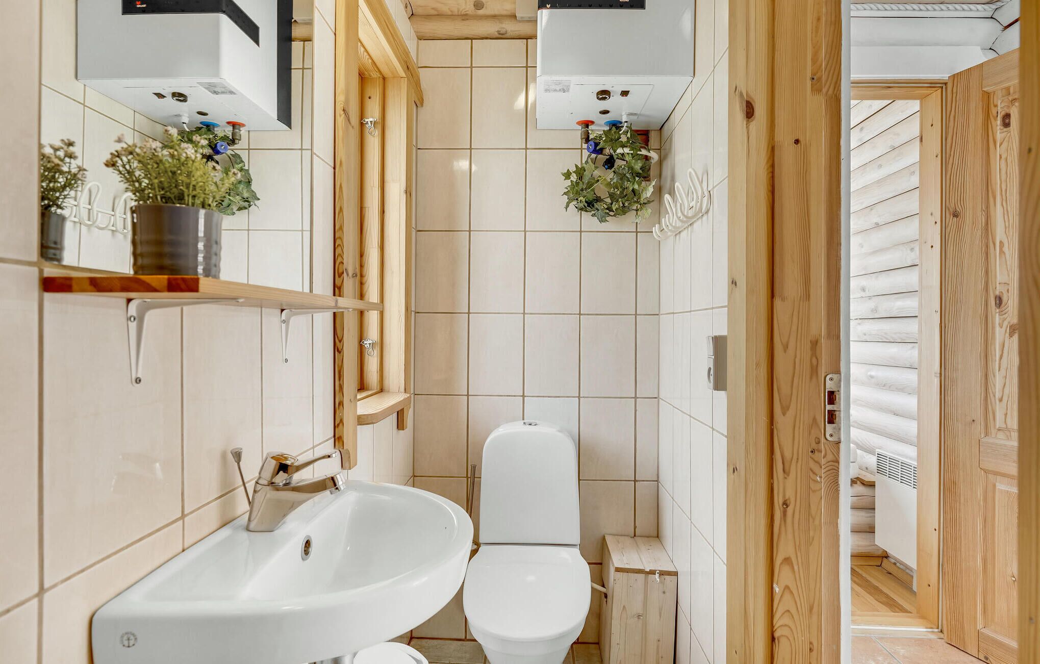Ein kleines Badezimmer mit einem weißen Waschbecken, Toilette und Holzschränken.