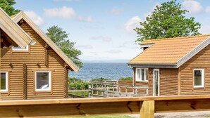 Two wooden cabins with a view of the sea, a wooden deck, and a grassy area. - 2 bedroom beautiful home in Tranekær (Tranekær)