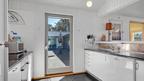 A modern kitchen with white cabinetry, a stainless steel sink, and a large window. - Gorgeous home in Blokhus with sauna (Blokhus)
