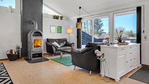 A modern living room with a fireplace, leather sofa, and a white dresser. - Gorgeous home in Blokhus with sauna (Blokhus)