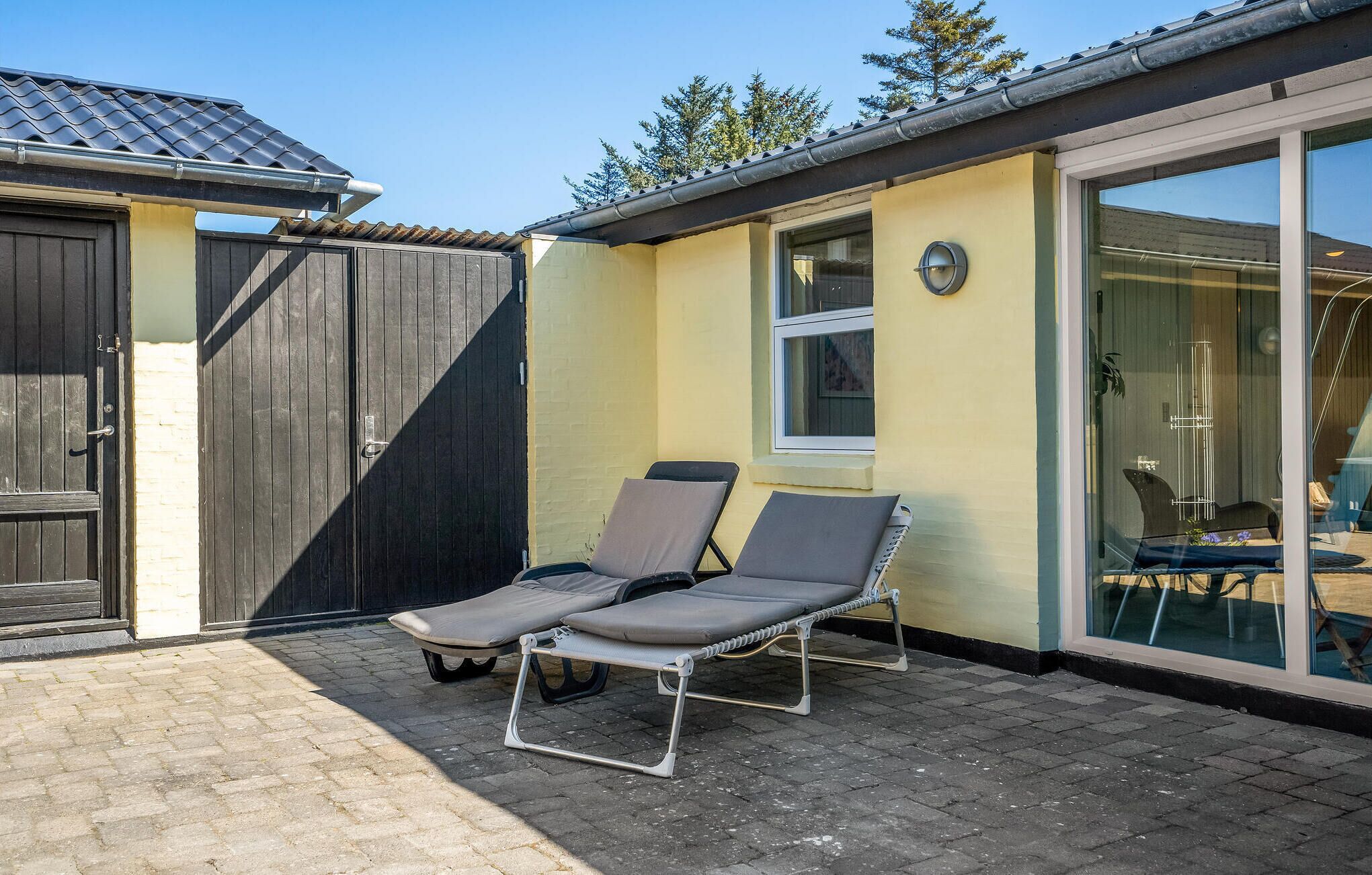 En terrasse med to liggestole og en skydedør, der fører til et indendørs område.
