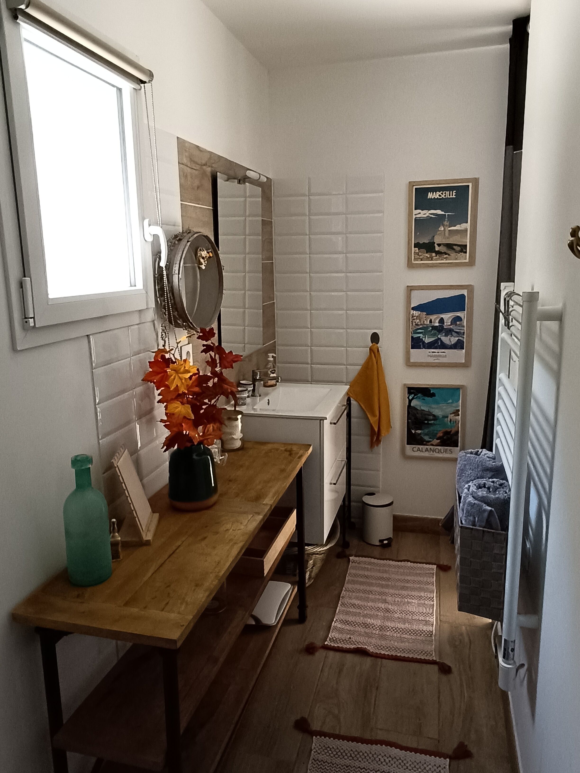 A compact bathroom with a wooden vanity, a mirror, a sink, and a towel rack.