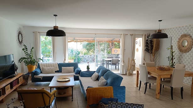 A living room with a sofa, coffee table, TV, and dining area with chairs and a table. - House close to activities and tourist sites (Labastide-de-Virac)
