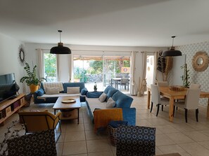 Un salon comprenant un canapé, une table basse, un téléviseur et un coin repas avec des chaises et une table.