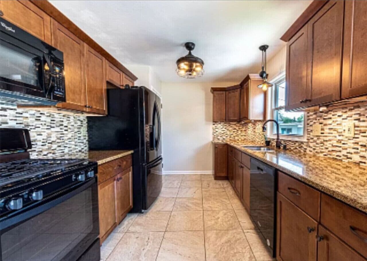 A kitchen with wooden cabinets, a black refrigerator, a stove, and a patterned backsplash.