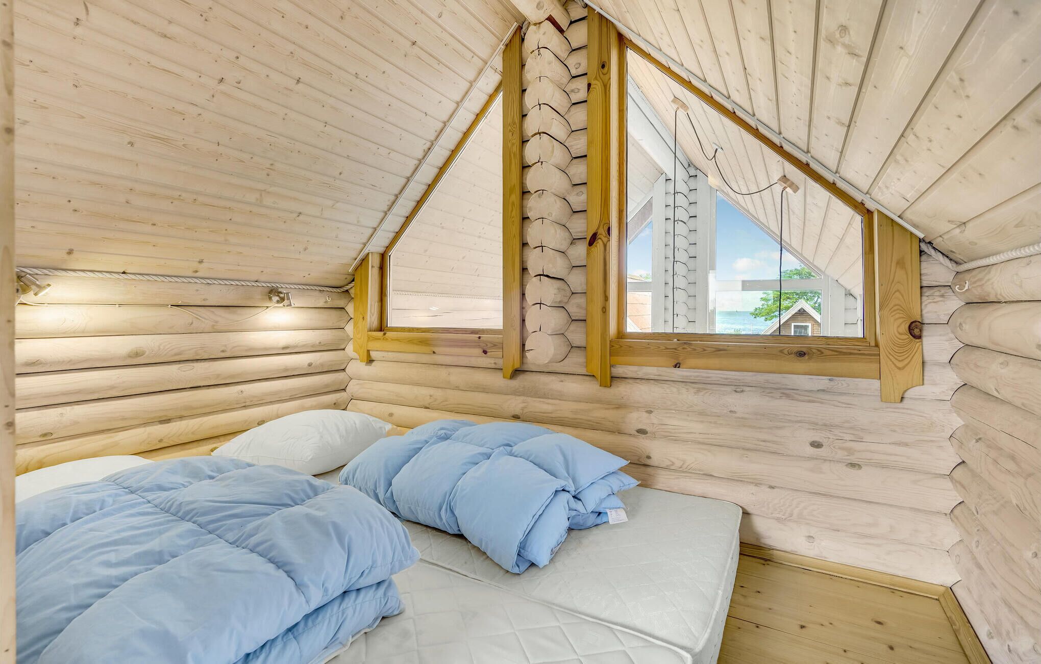 Et hyggeligt træsområde med et bed, et vindue og udsigt udad.