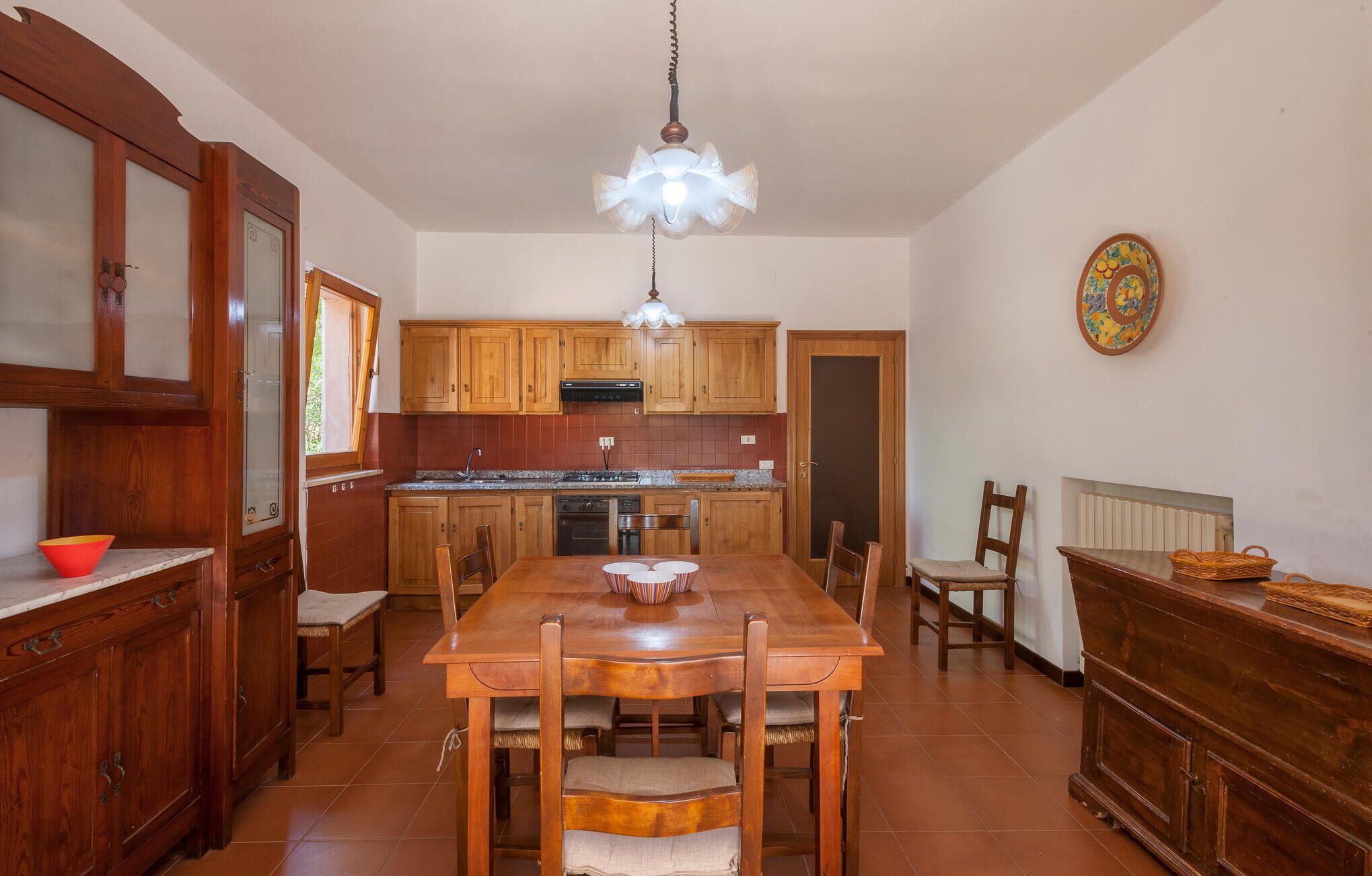 A kitchen with wooden cabinets, a central island, and a dining table with chairs.