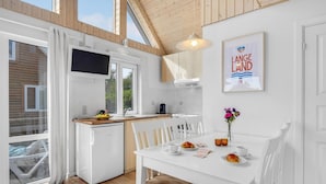A modern kitchen with white cabinetry, a built-in oven, and a dining area with a white table and chairs. - Pet friendly home in Tranekær with WiFi (Tranekær)
