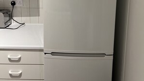 A white Bosch refrigerator with a control panel on top, a power outlet, and a white countertop with a toaster. - Charming Apartment Garden View (London)