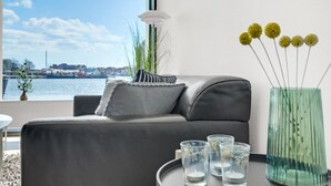 A modern living room with a grey sofa, striped pillow, and a vase with yellow flowers. - Amazing apartment in Korsør (Korsør)