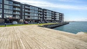 A modern multi-story building with balconies, a wooden deck, and a waterfront view. - Amazing apartment in Korsør (Korsør)