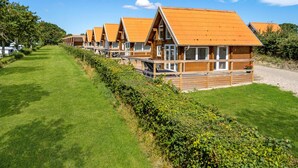 Une rangée de cabanes en bois aux toits inclinés, chacune dotée d’un balcon et d’une fenêtre.