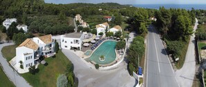 An aerial view of a coastal property with a swimming pool, multiple buildings, and a road. - Greek Pride Aithrion Hotel (Kassandra)