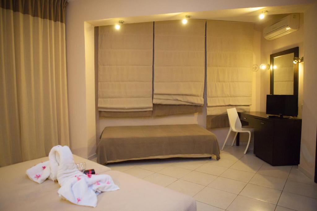 Ein Hotelzimmer mit Bett, Schreibtisch, Stuhl, Fernseher und Spiegel.
