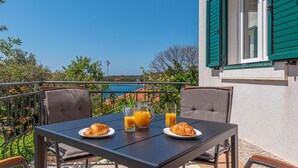 Ein Tisch mit Croissants und Orangensaft mit Blick auf eine malerische Küstenlandschaft.
