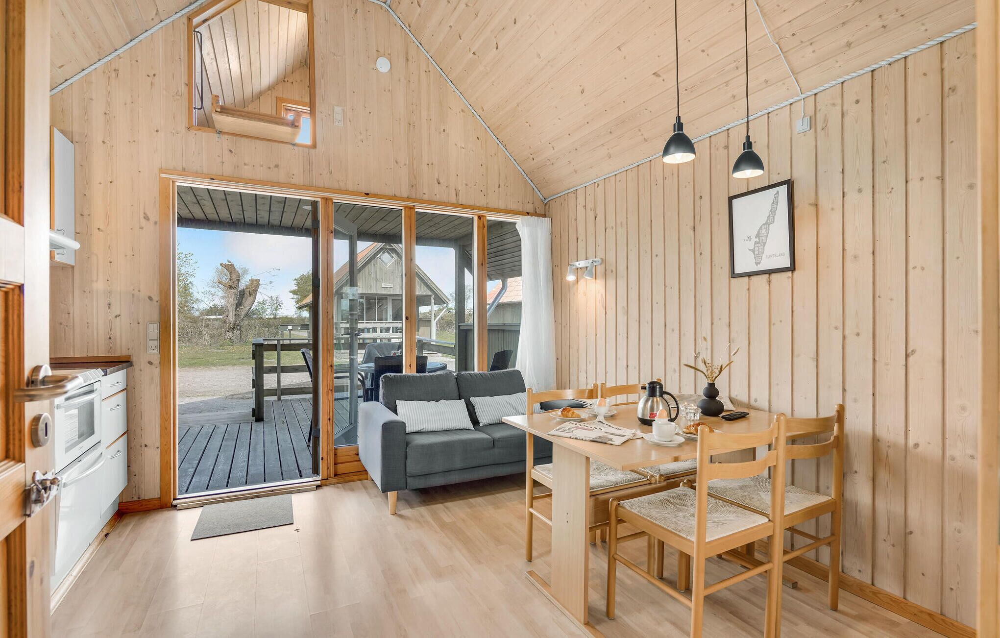 Ein gemütliches Blockhaus-Interieur mit Holzausstattung, einem Essbereich mit Tisch und Stühlen, einer Couch und Blick ins Freie.