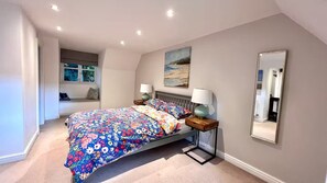 Un dormitorio con una cama, lámparas de noche, una ventana, un cuadro y un espejo.